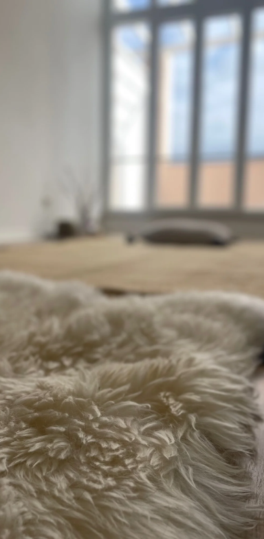 Heller Raum mit einem Schafsfell im Vordergrund und der Massagematte im Hintergrund
